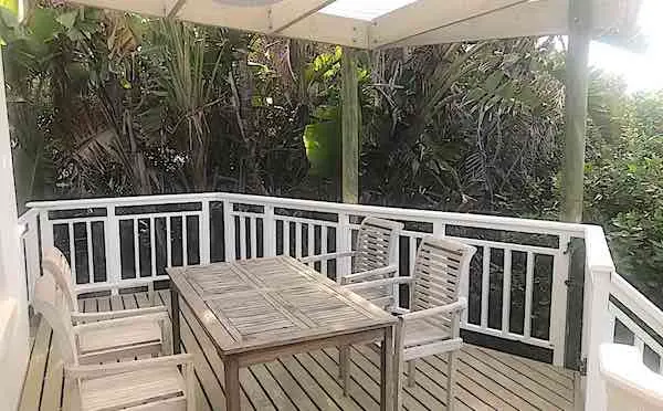 An outdoor table and chairs on a shaded wooden deck