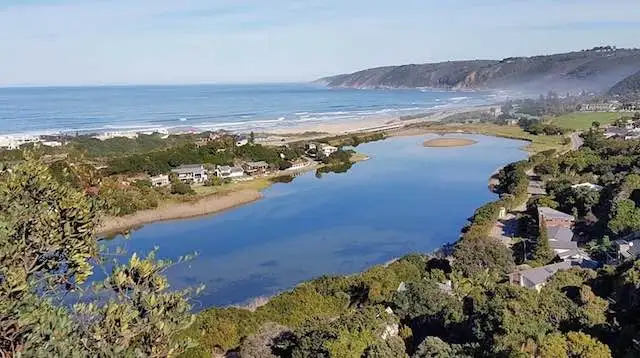 The Wilderness lagoon alongside the beach and green coastal hills